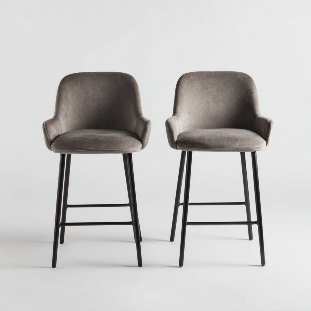 Juego de 2 taburetes de bar con asientos de terciopelo gris y patas de metal negro.